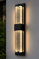Installed view of 18-inch LED crystal bubble glass outdoor wall sconce mounted on exterior wall with warm illuminated bubble acrylic diffuser, black aluminium frame and modern architectural lighting design.