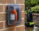 TayMac MM410CCN weatherproof in-use outlet cover installed on exterior brick wall with extension cord plugged into outdoor GFCI receptacle during wet conditions in Canada